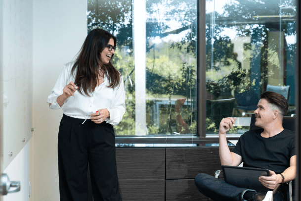 A woman at a whiteboard discusses Austin Public Relations crisis management with a man focused on social media consulting on a tablet.