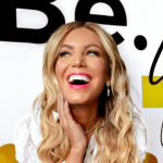 Woman with long blonde hair smiling confidently in front of "Be" backdrop, representing Austin Public Relations and Social Media expertise.