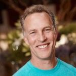 Dr. Gary L. Cash, smiling in a teal shirt indoors, evokes the confidence and warmth of an Austin Public Relations leader in social media and crisis management consulting.