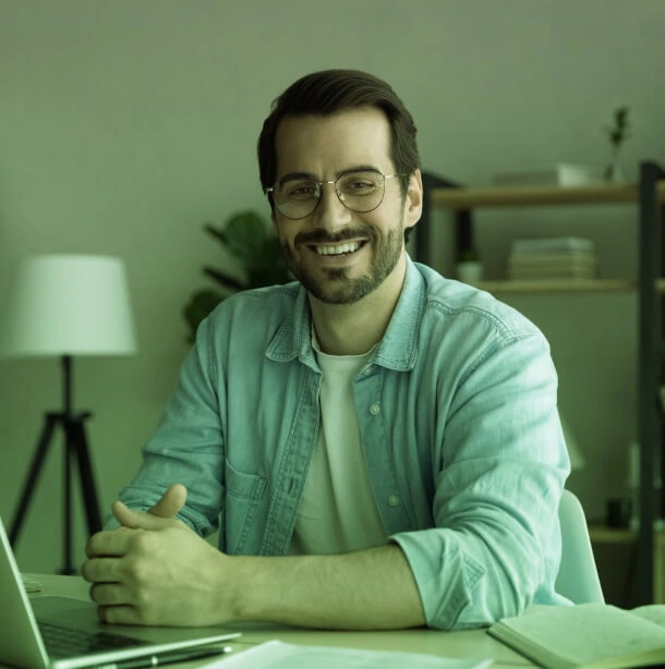A bearded man with glasses smiles at a laptop, immersed in Austin Public Relations consulting and social media management.