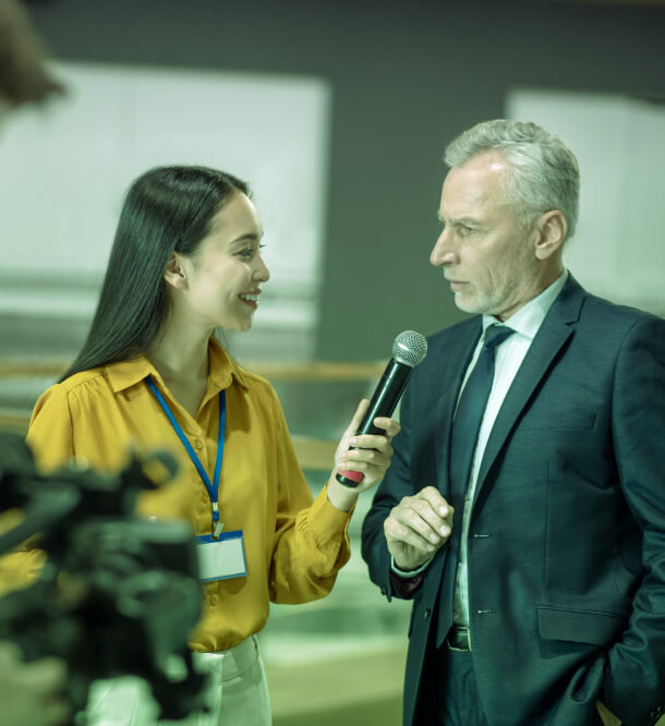 A woman in a yellow shirt interviews a man in a suit for an Austin PR agency, discussing Public Relations and Crisis Management strategies.