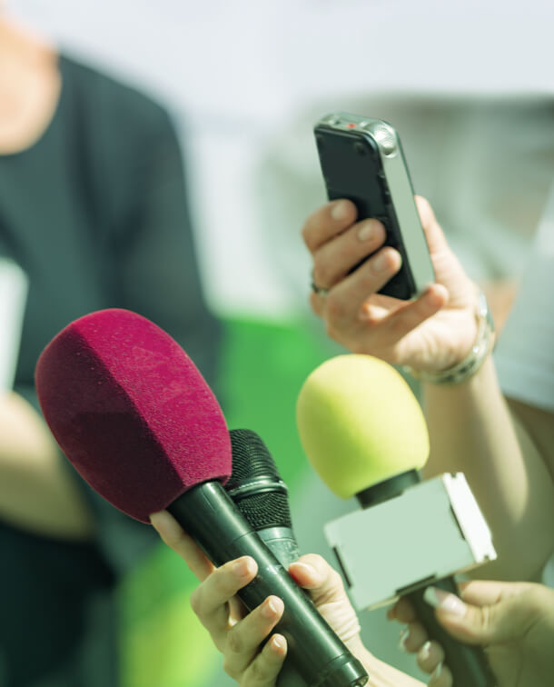 Hands hold microphones and a recording device during an Austin PR interview, capturing insights on social media and crisis management.