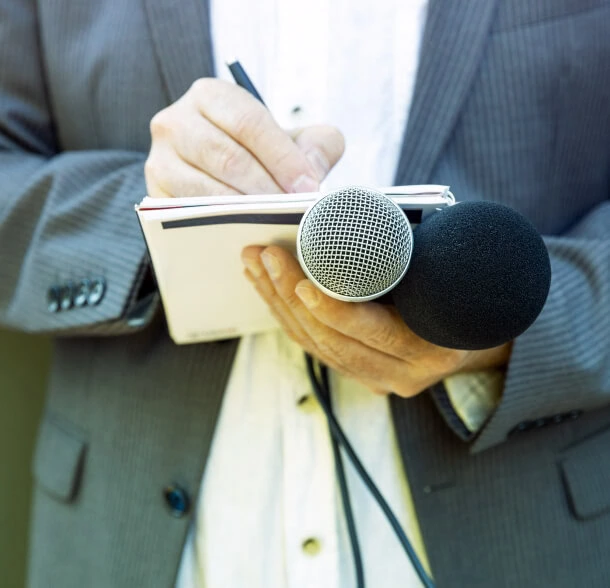 A professional in a suit, representing Austin PR expertise, holds microphones and a notebook for consulting on crisis management strategies.