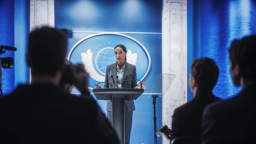 A woman speaking onstage at a political event.