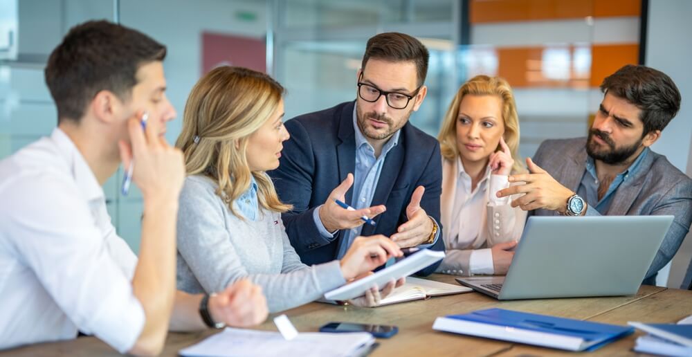 Five people discuss Austin Public Relations strategies at a table, focusing on crisis management, social media, and press releases.