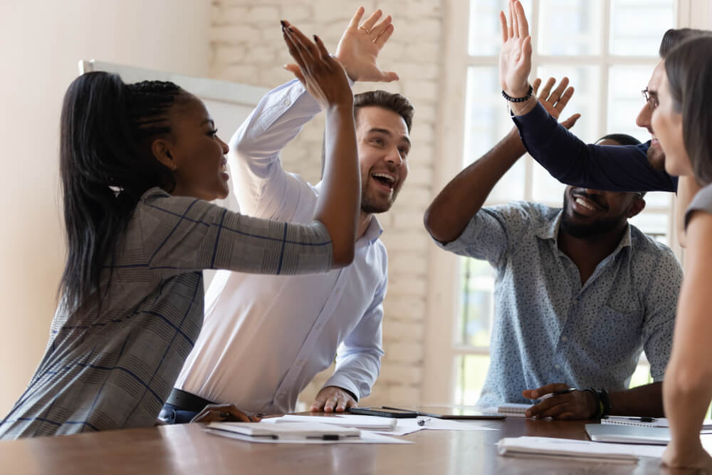 A group celebrates in an Austin office, exchanging high fives for effective crisis management strategies in digital PR and social media.